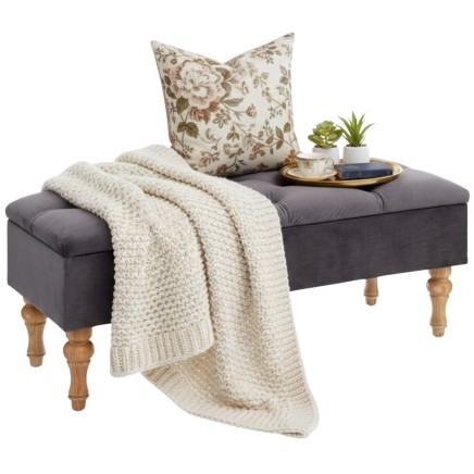 Banco tapizado gris oscuro con patas de madera y cojín floral estampado en ambiente decorado