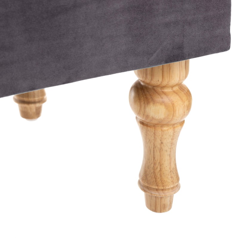 Detalle de pata de baúl tapizado en gris oscuro con pata de madera torneada color natural