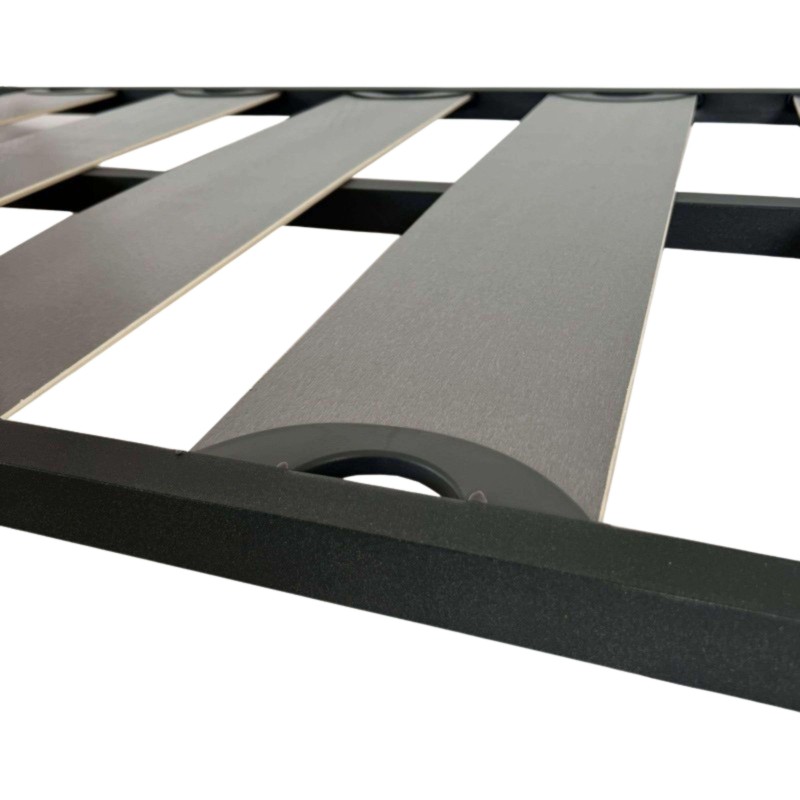 Cama con estructura negra y láminas grises y blancas alternadas con asas laterales en detalle de sistema de soporte