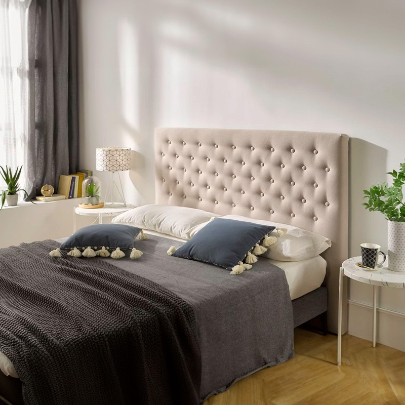 Cama con cabecero tapizado en beige y botones decorativos en dormitorio moderno