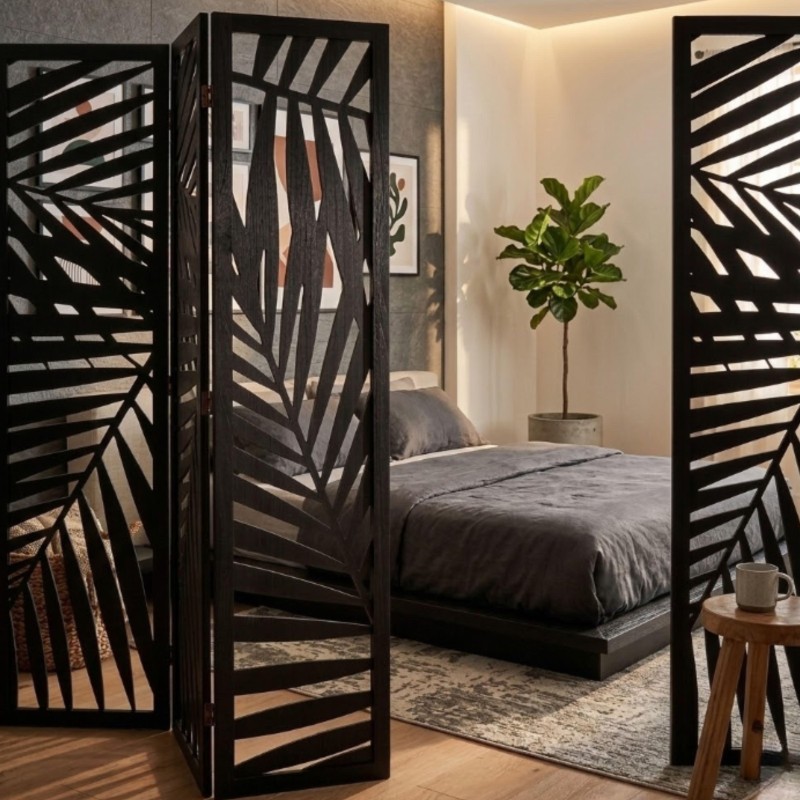 Biombo divisor negro con diseño de hojas caladas y espejo central en dormitorio moderno con cama y planta