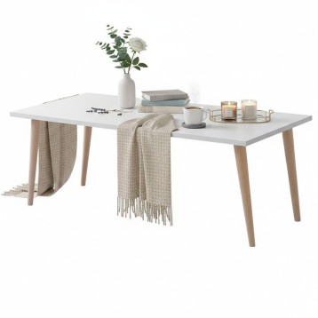 Mesa de comedor blanca con patas de madera clara y decoración de flores y velas