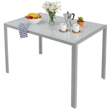 Mesa de comedor rectangular gris claro con cubierta brillante y estructura metálica minimalista decorada con frutas y accesorios