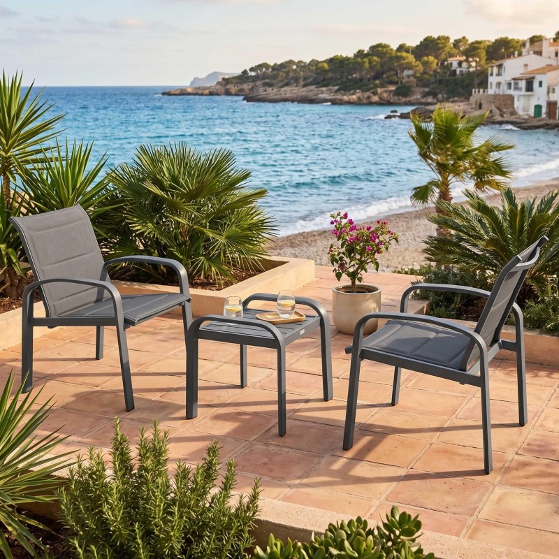 Conjunto de terraza con dos sillones y mesita auxiliar de estructura gris y asientos textil en ambiente de playa mediterránea