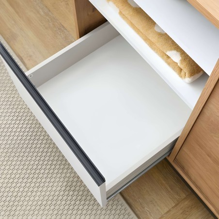 Detalle de cajón abierto en blanco y madera natural con tirador gris y toallas de baño beige en interior