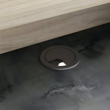 Detalle de pasacables circular negro en tablero de escritorio madera clara y estructura oscura