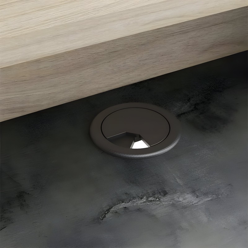 Detalle de pasacables circular negro en tablero de escritorio madera clara y estructura oscura