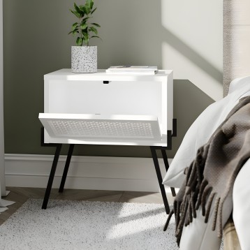 Mesita de noche blanca con cajón y patas negras en dormitorio junto a cama