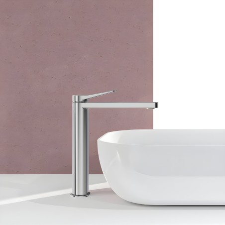 Grifo de baño monocomando alto en cromo pulido junto a lavamanos blanco en ambiente de baño moderno