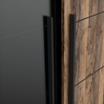 Detalle de tirador negro alargado en puerta de madera rústica clara con marco gris