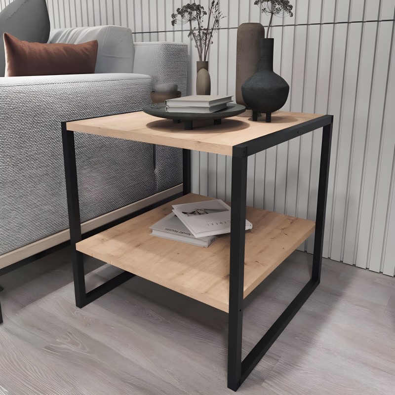 Mesita auxiliar con tableros de madera clara y estructura metálica negra junto a sofá gris en ambiente de sala