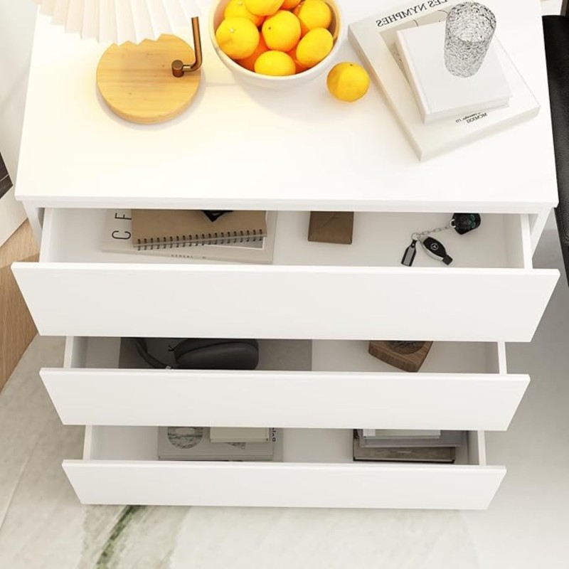 Cómoda blanca con tres cajones abiertos y tablero superior con cuenco blanco y objetos decorativos vista cenital