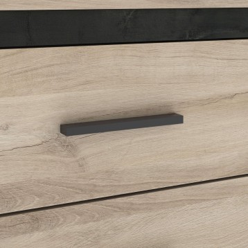 Detalle de tirador negro metálico en cajón de madera clara con acabado natural
