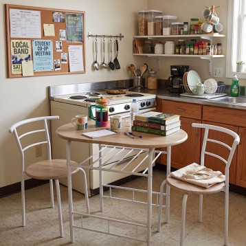 Mesa de comedor ovalada madera clara con estructura blanca y dos sillas respaldo curvo en cocina
