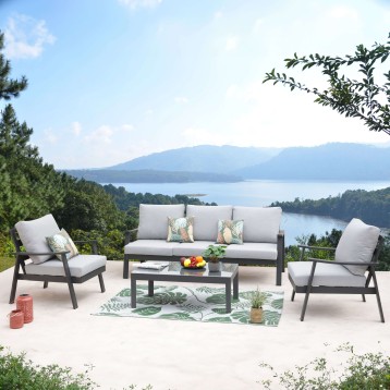 Conjunto de sofá y sillones de exterior con estructura negra y cojines grises y mesa de centro en terraza frente al lago