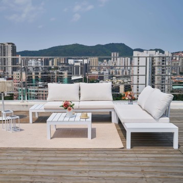 Conjunto de sofá modular blanco con cojines y mesa de centro en terraza con vistas a ciudad y montañas