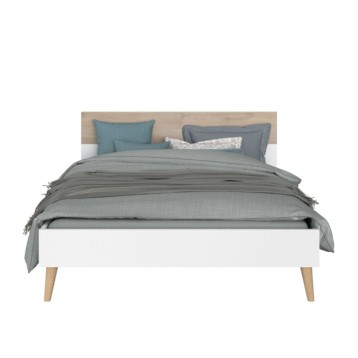 Cama blanca con cabecero tapizado en tonos grises y beige con patas de madera natural y ropa de cama gris y almohadas azules