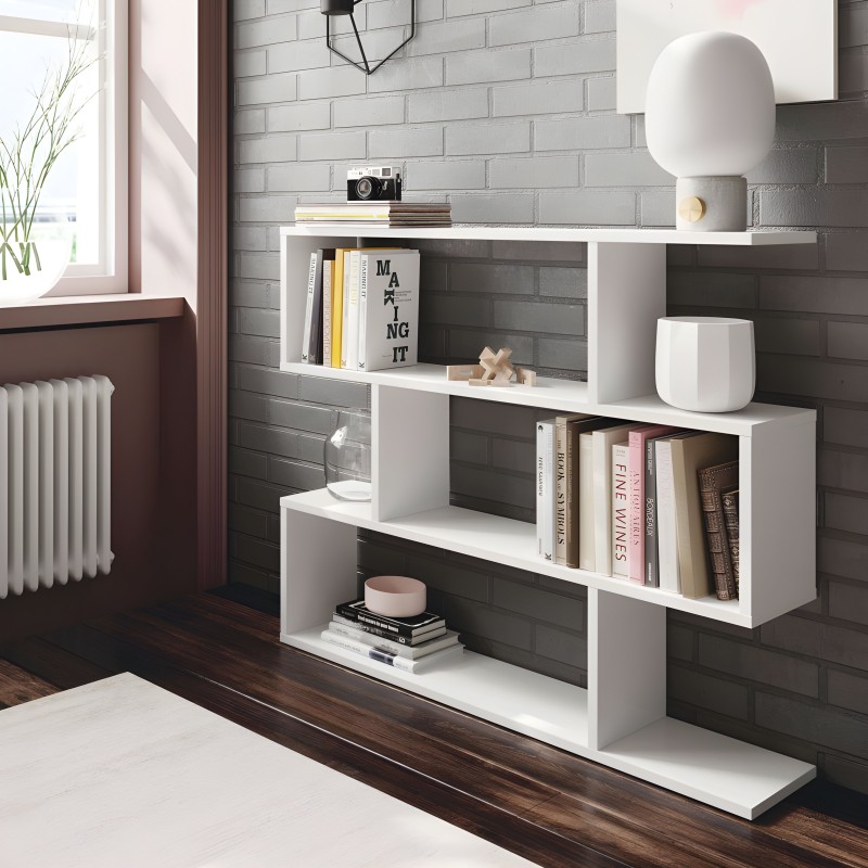 Estantería modular blanca con múltiples compartimentos abiertos en ambiente de sala con pared de ladrillo gris y libros decorati
