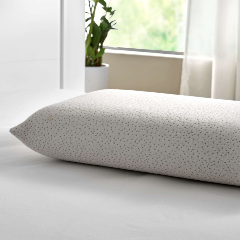Almohada rectangular en tela gris claro con textura puntillada en ambiente de dormitorio luminoso