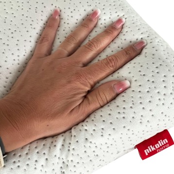 Detalle de tela blanca perforada con textura y mano mostrando superficie suave
