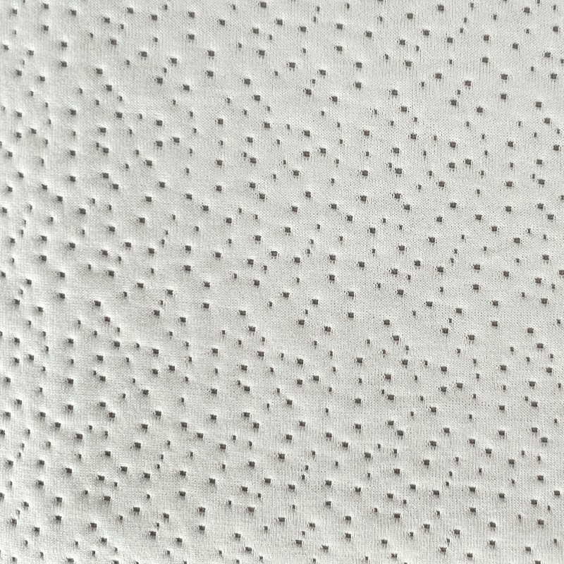 Detalle de tapizado en tela beige con textura de relieve puntillado y acabado acolchado