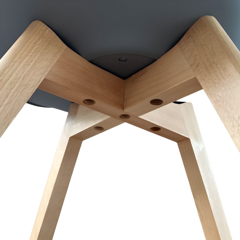 Silla con patas de madera clara cruzadas y asiento redondeado vista desde abajo