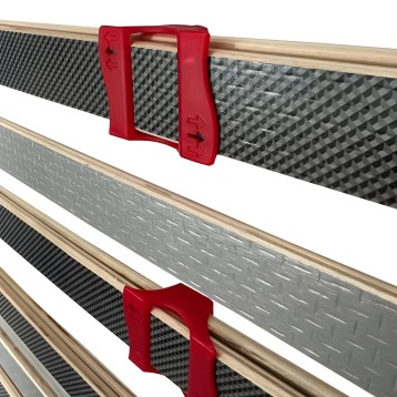 Cama con baranda de seguridad roja y barrotes grises textilizados sobre estructura de madera natural