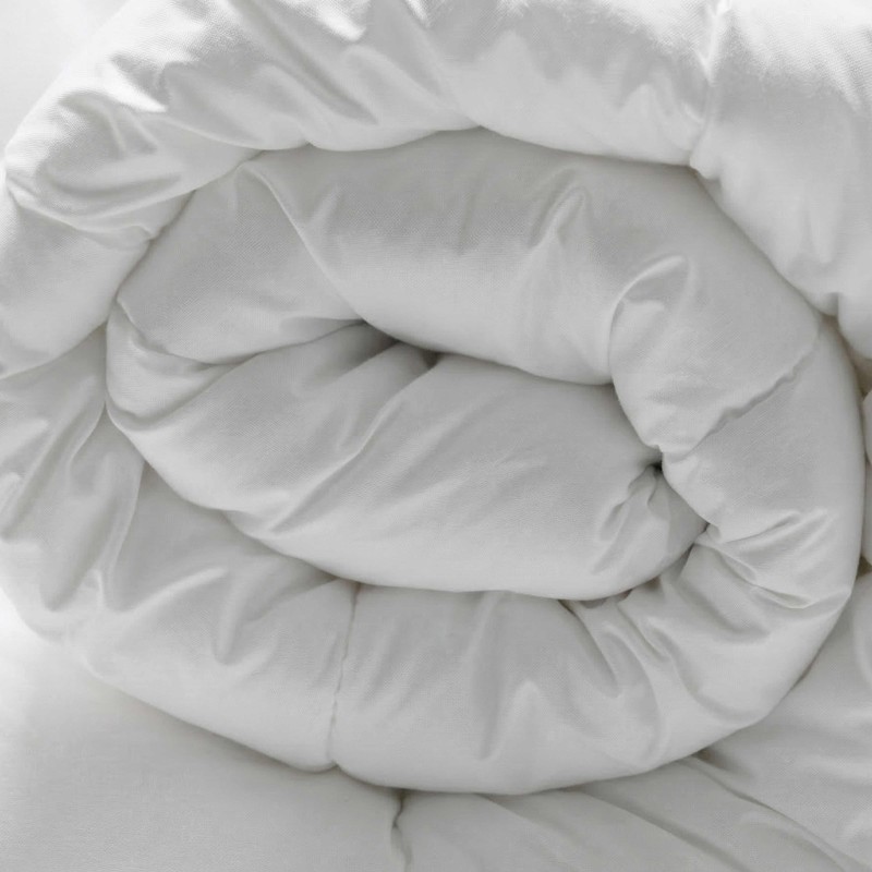 Detalle de ropa de cama blanca enrollada y plegada mostrando la textura del tejido suave
