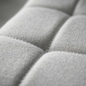 Detalle de tapizado en tela gris claro con costuras y pliegues de sofá o sillón