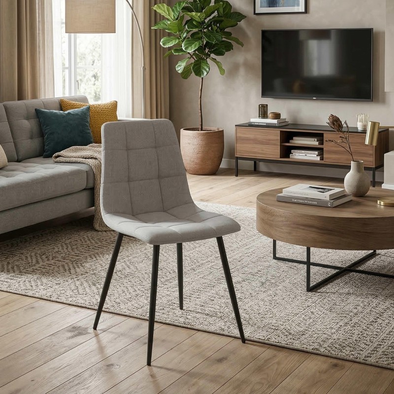Silla de comedor con tapizado gris claro y patas metálicas negras en ambiente de sala de estar moderna