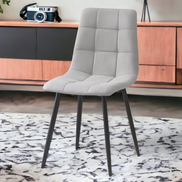 Silla moderna tapizada en gris claro con respaldo acolchado y patas metálicas negras en ambiente de interior