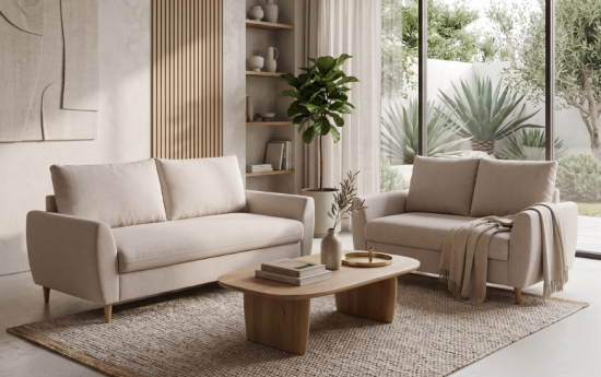Dos sofás biplaza beige de tela en salón nórdico luminoso con estantería, planta y mesa de centro ovalada